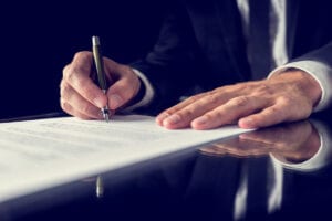 man's hands holding fountain pen signing legal document