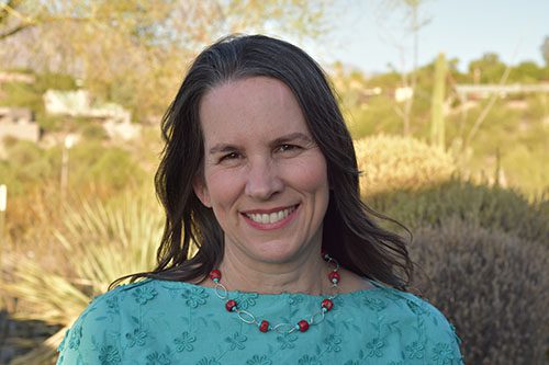 Photo of Robin Singer, Realtor outside in sunny Tucson, smiling and eager to help you buy or sell real estate, with desert greenery behind her