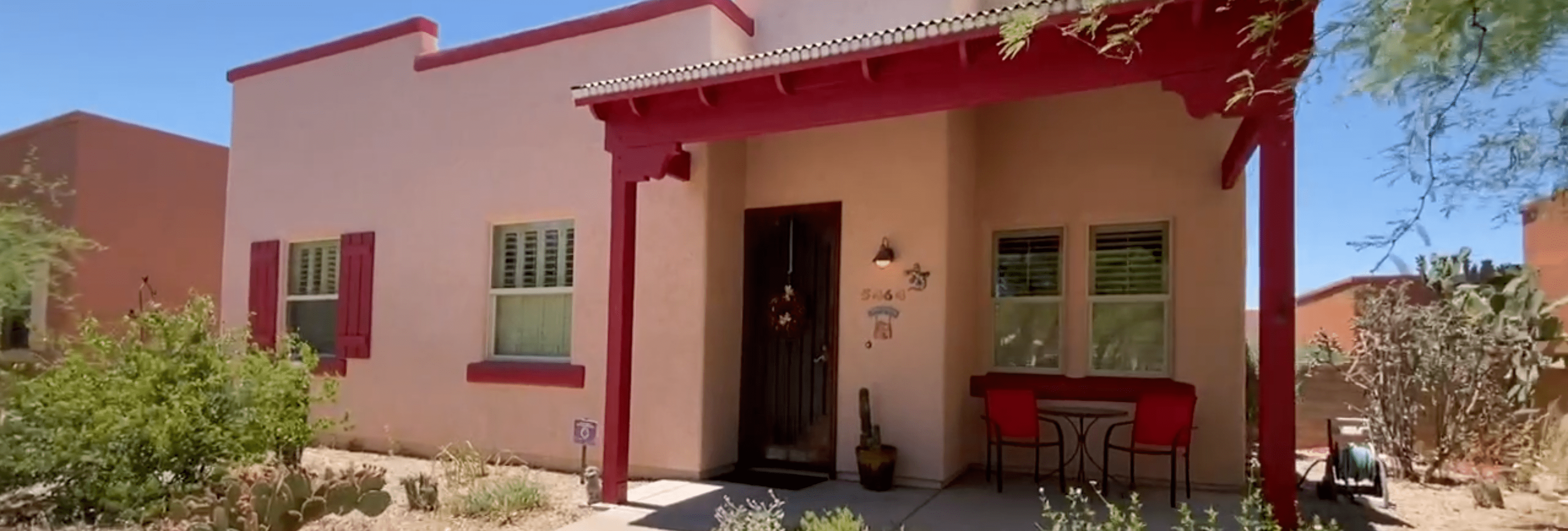 Photo of Civano Home - pink house with red trim and a covered porch with a table and two chairs under it -in Tucson's Masterplanned Community for Sustainability
