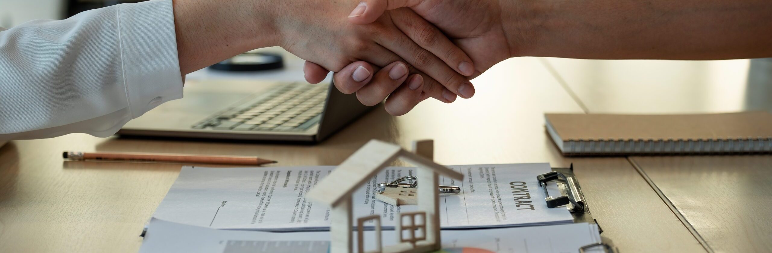 Handshake a successful real estate transaction in an office. Business people shake hands after signing a house purchase agreement.